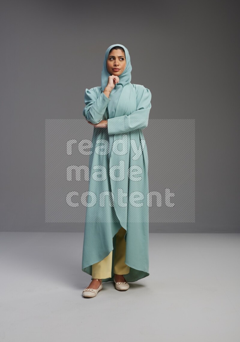 Saudi Woman wearing Abaya standing interacting with the camera on Gray background