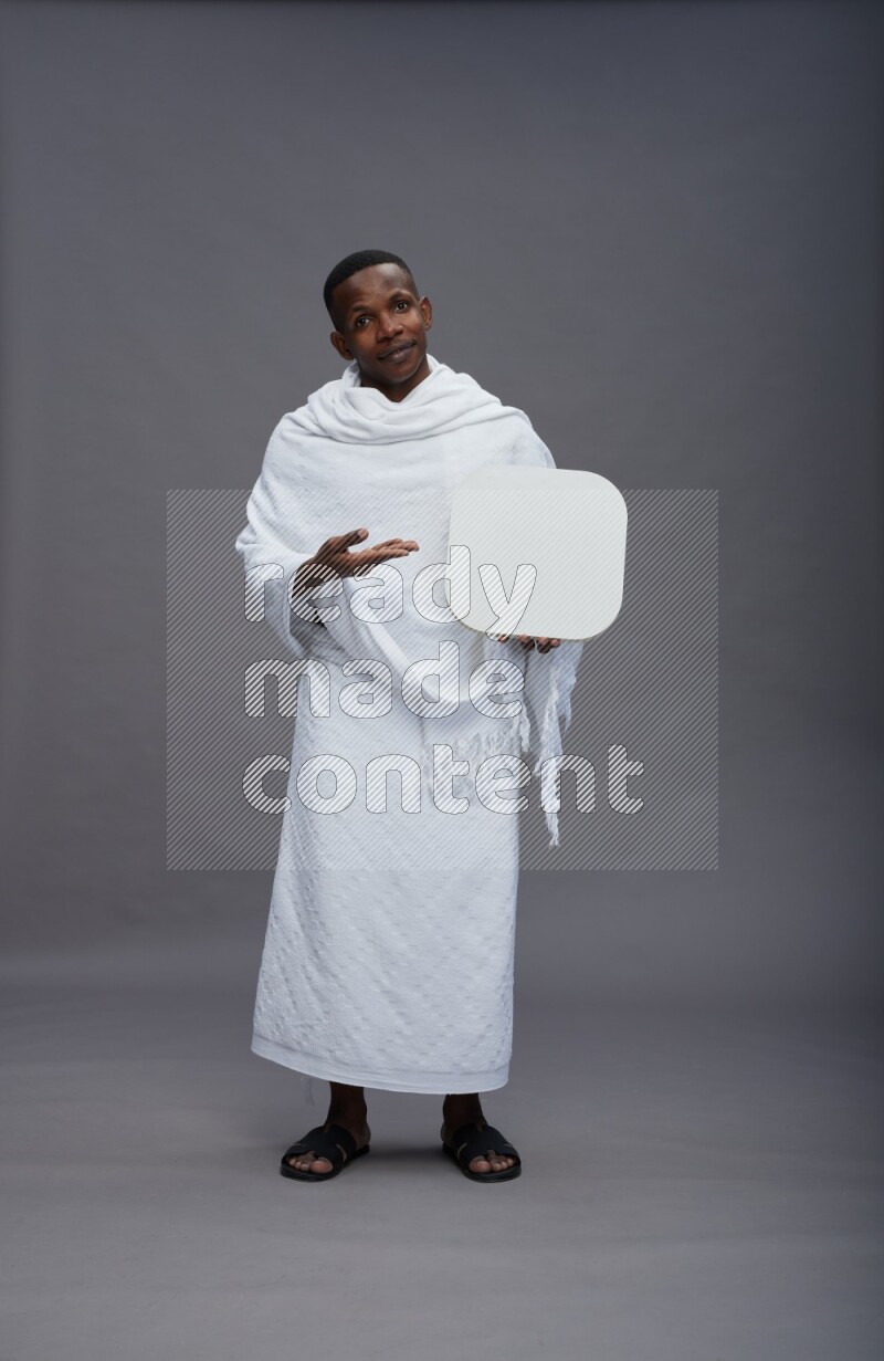 A man wearing Ehram Standing holding social media sign on gray background