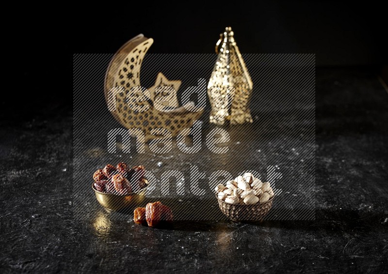 Dates in a metal bowl with pistachios beside golden lanterns in a dark setup