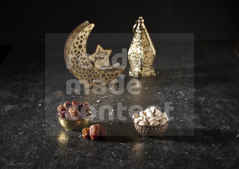 Dates in a metal bowl with pistachios beside golden lanterns in a dark setup