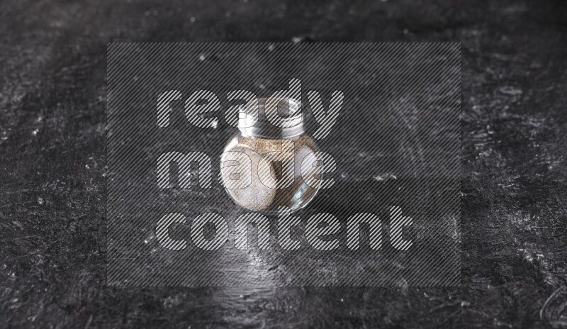 بودرة الفلفل الأسود في وعاء زجاجي علي خلفية سوداء