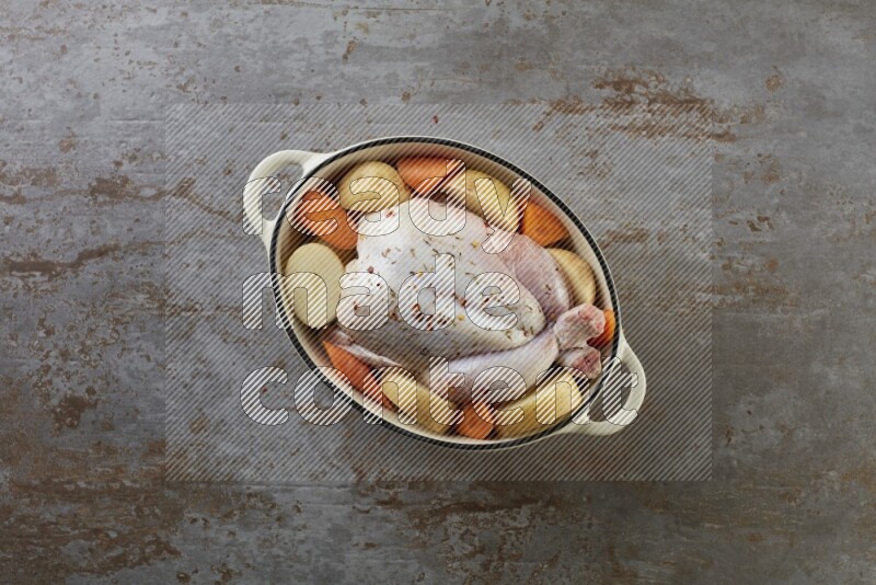 whole raw chicken on in a white ceramic pot direct on a rustic grey background