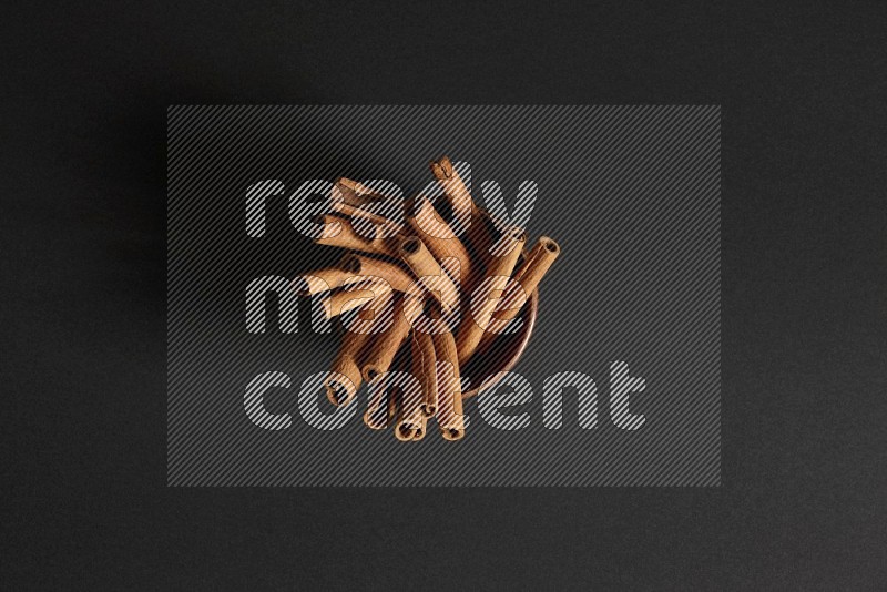 Cinnamon Sticks in a wooden bowl on black background