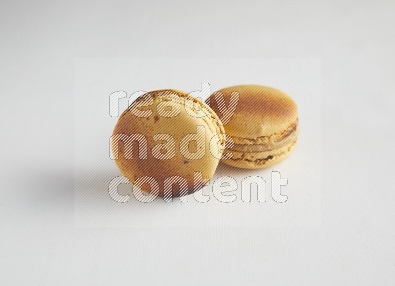 45º Shot of two Yellow Crème Brulée macarons on white background