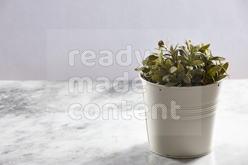 Green artificial plant in white pot on light grey marble background