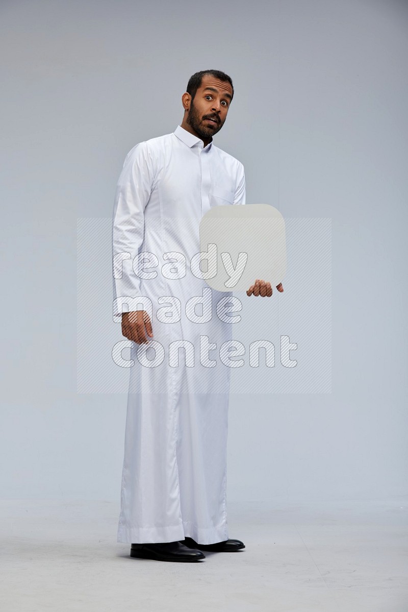 Saudi man wearing Thob standing holding social media sign on Gray background