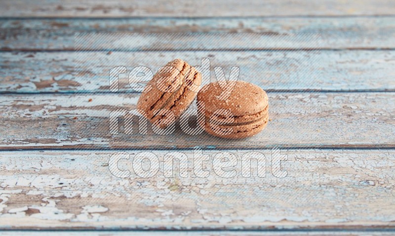 45º Shot of two Brown Hazelnuts macarons on light blue wooden background