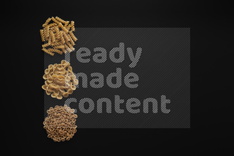 Different pasta types in 3 bunches on black background