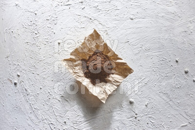 Cloves powder on crumpled piece of paper on a textured white flooring