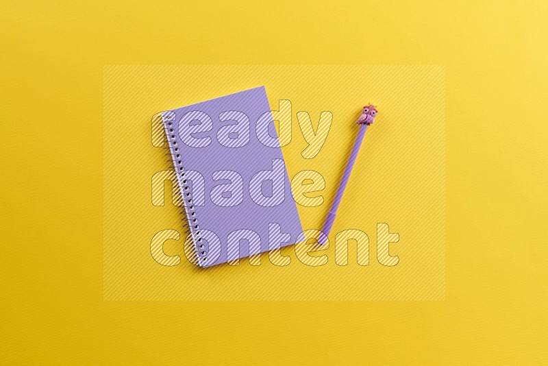 A purple notebook with school supplies on yellow background (Back to school)
