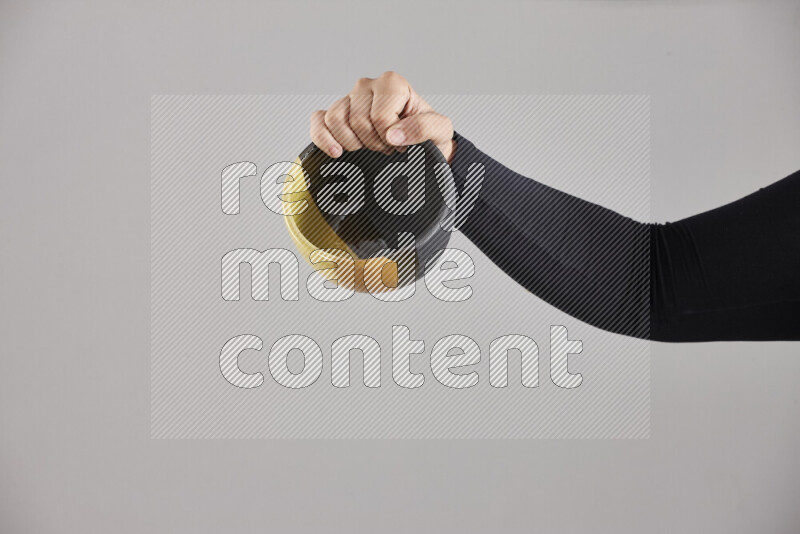A woman in black abaya holding different pottery essentials in different positions