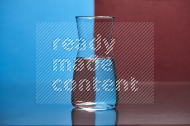 The image features a clear glassware filled with water, set against blue and dark red background