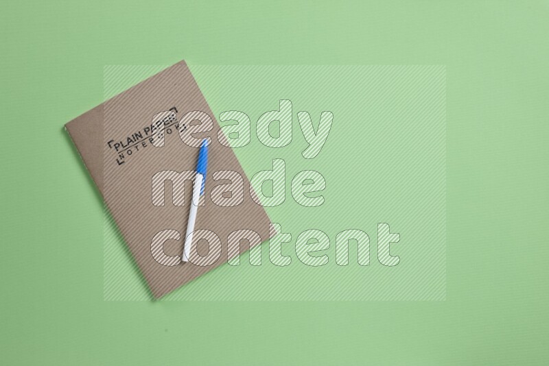 A notebook with different school supplies on green background