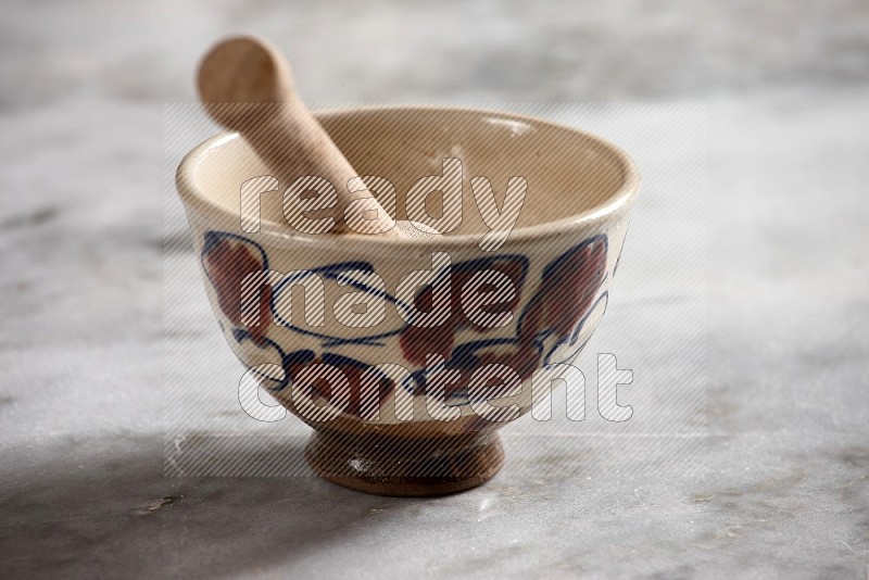 Decorative Pottery Bowl with wooden honey handle in it, on grey marble flooring, 15 degree angle