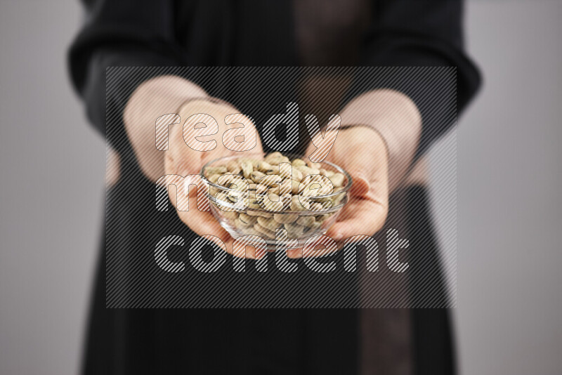 Woman in abaya holding different kinds of legumes in different positions