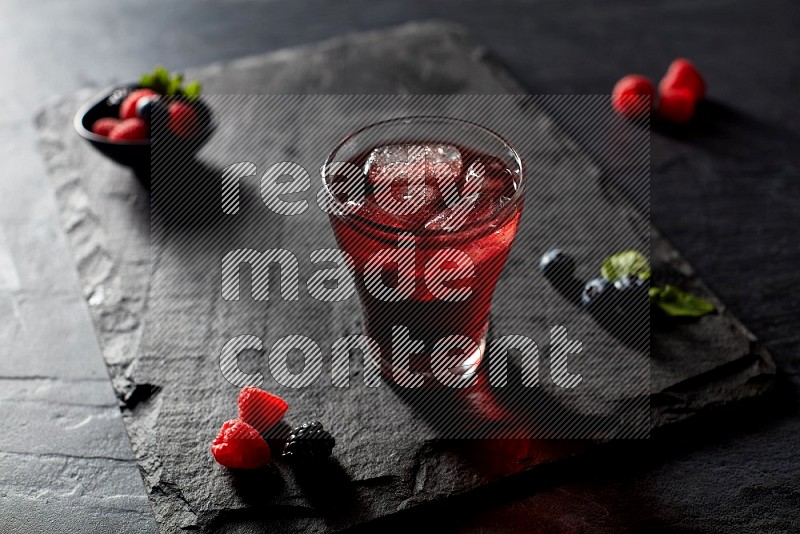 A glass of mixed berries juice on black background