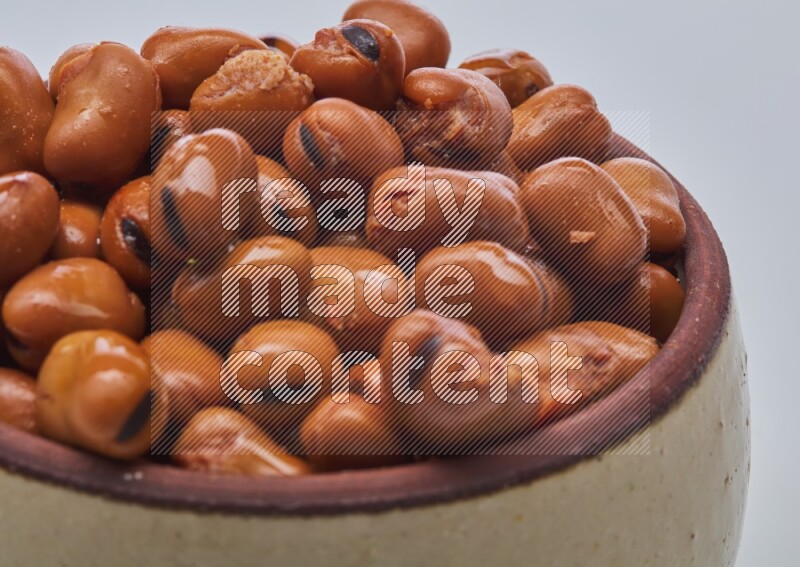 Close up shot of cooked fava beans (foul) in a container on white background