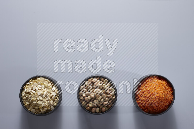 Legumes in pottery bowls on light grey background