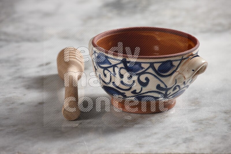 Decorative pottery pot with wooden honey dipper on the side on grey marble background