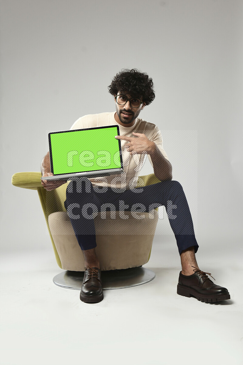 A man wearing casual sitting on a chair showing a laptop screen on white background