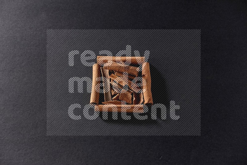 A single square of cinnamon sticks full of cinnamon on black flooring