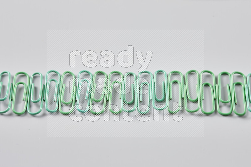 Green paper clips isolated on a grey background