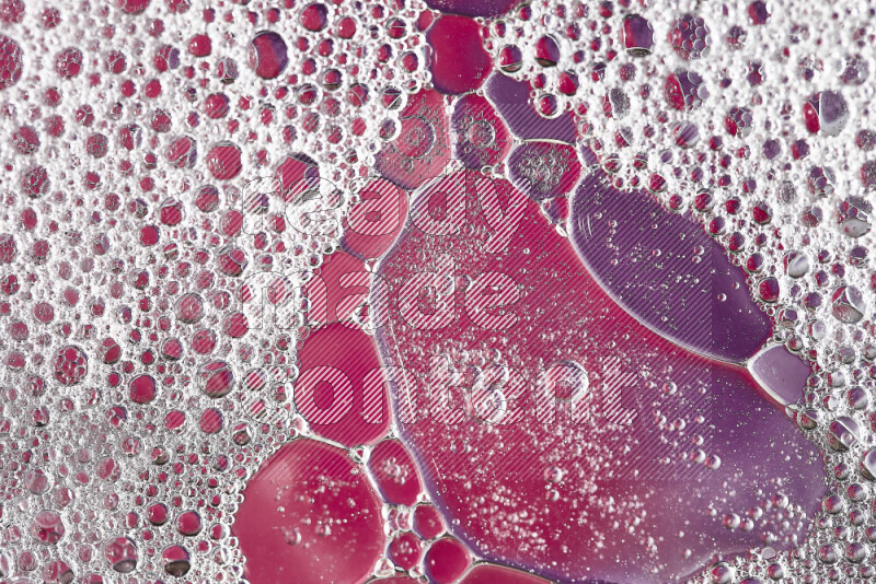 Close-ups of abstract soap bubbles and water droplets on pink and purple background