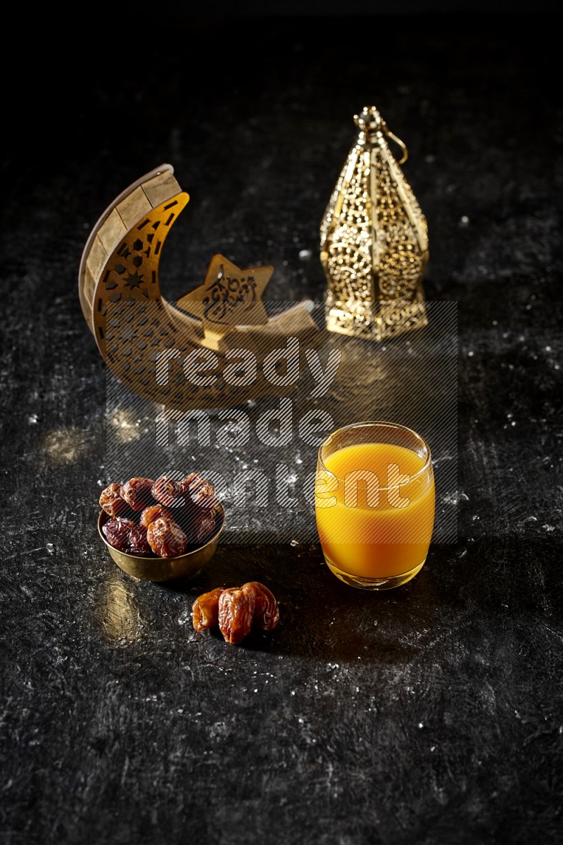 Dates in a metal bowl with qamar el din beside golden lanterns in a dark setup