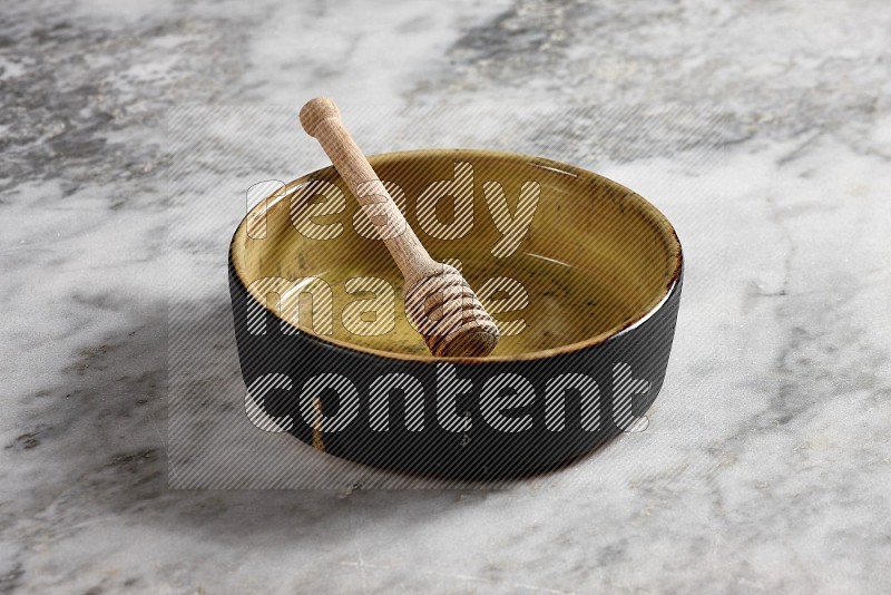 Multicolored Pottery Oven Plate with wooden honey handle in it, on grey marble flooring, 45 degree angel