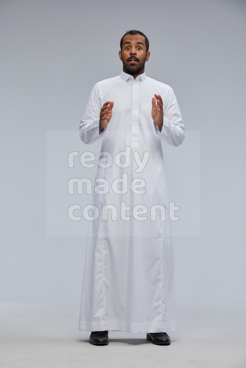 Saudi man Wearing Thob standing interacting with the camera on Gray background