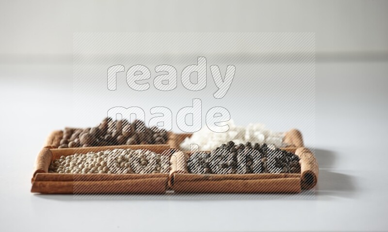 4 squares of cinnamon sticks full of allspice, white salt, white pepper and black pepper on white flooring