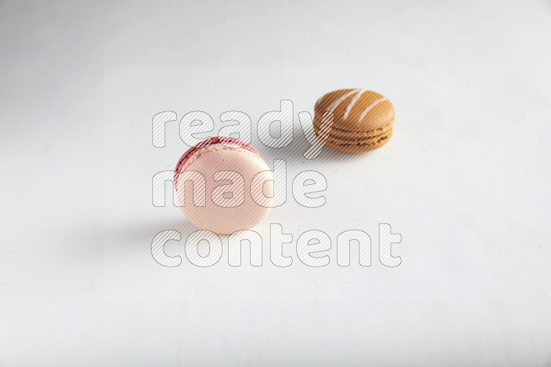 45º Shot of of two assorted Brown Irish Cream, and Pink Litchi Raspberry macarons on white background