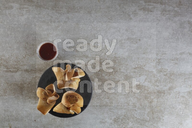 wonton cups with soy sauce ramkin on circle slate on grey textured counter top