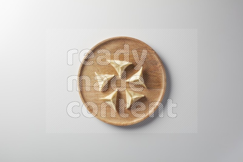 Five Sambosas on a wooden round plate on a white background