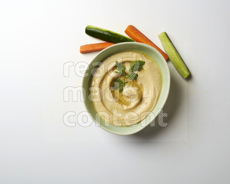 Hummus in a green plate garnished with parsley on a white background