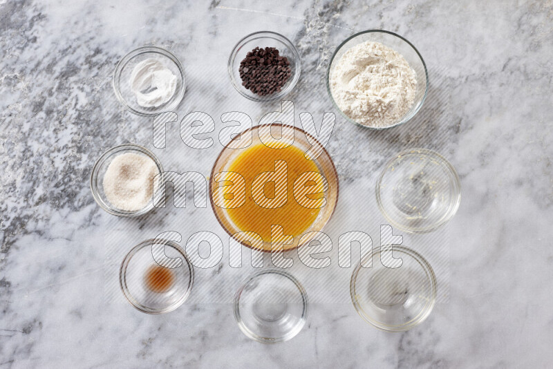 Cookies step by step with its ingredient, flour, butter, brown sugar, egg, vanilla extract, white sugar, chocolate chips and baking soda on grey marble background