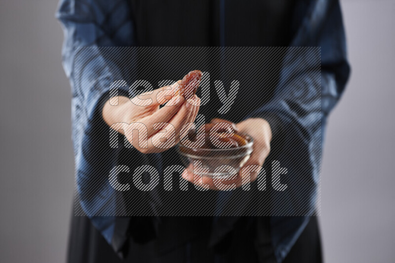 Woman in abaya holding dates in different positions