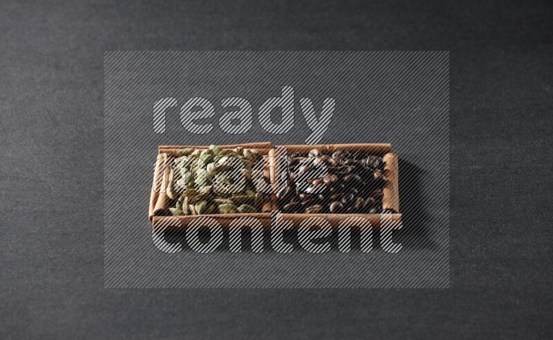 مربعان من أعواد القرفة ممتلئان بحبوب القهوة وحبوب الهيل علي خلفية سوداء