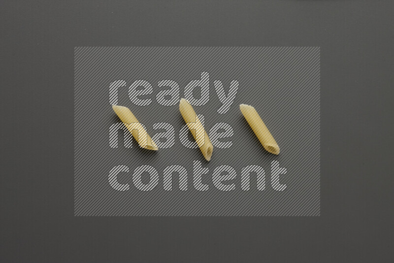 Mini penne pasta on grey background
