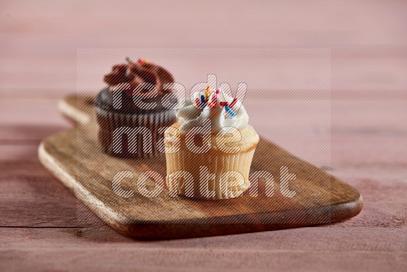 Vanilla mini cupcake topped with cream on a wooden board