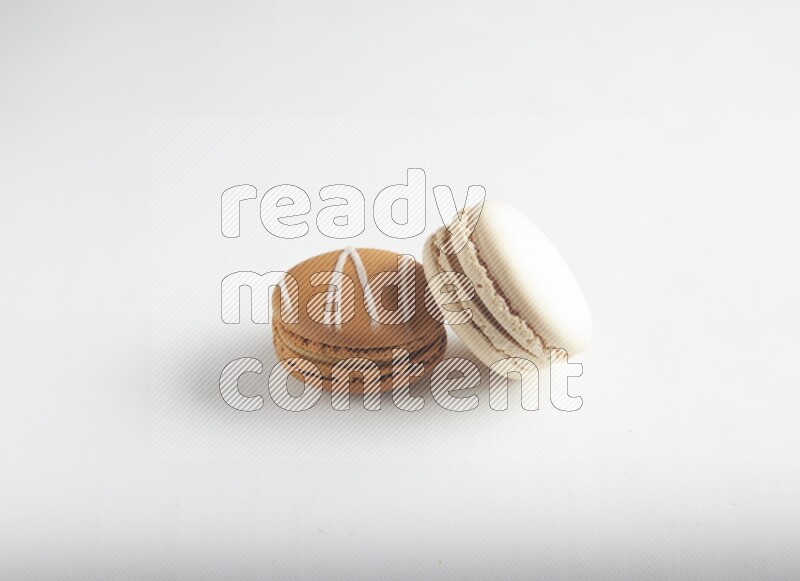 45º Shot of of two assorted Brown Irish Cream, and White Caramel fleur de sel macarons on white background