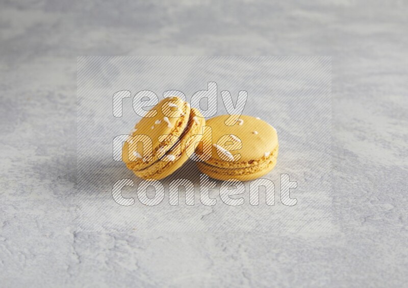 45º Shot of two Yellow Piña Colada macarons  on white  marble background