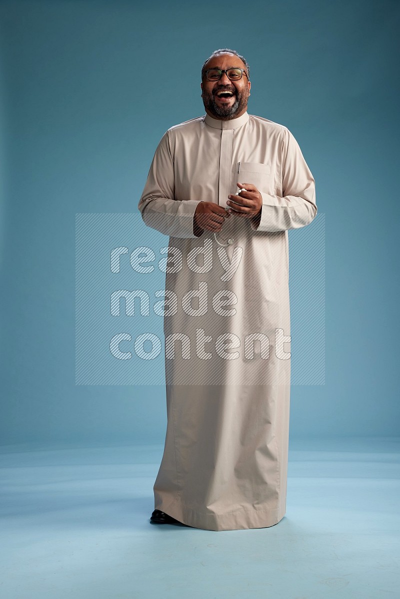 Saudi Man without shimag Standing Interacting with the camera on blue background