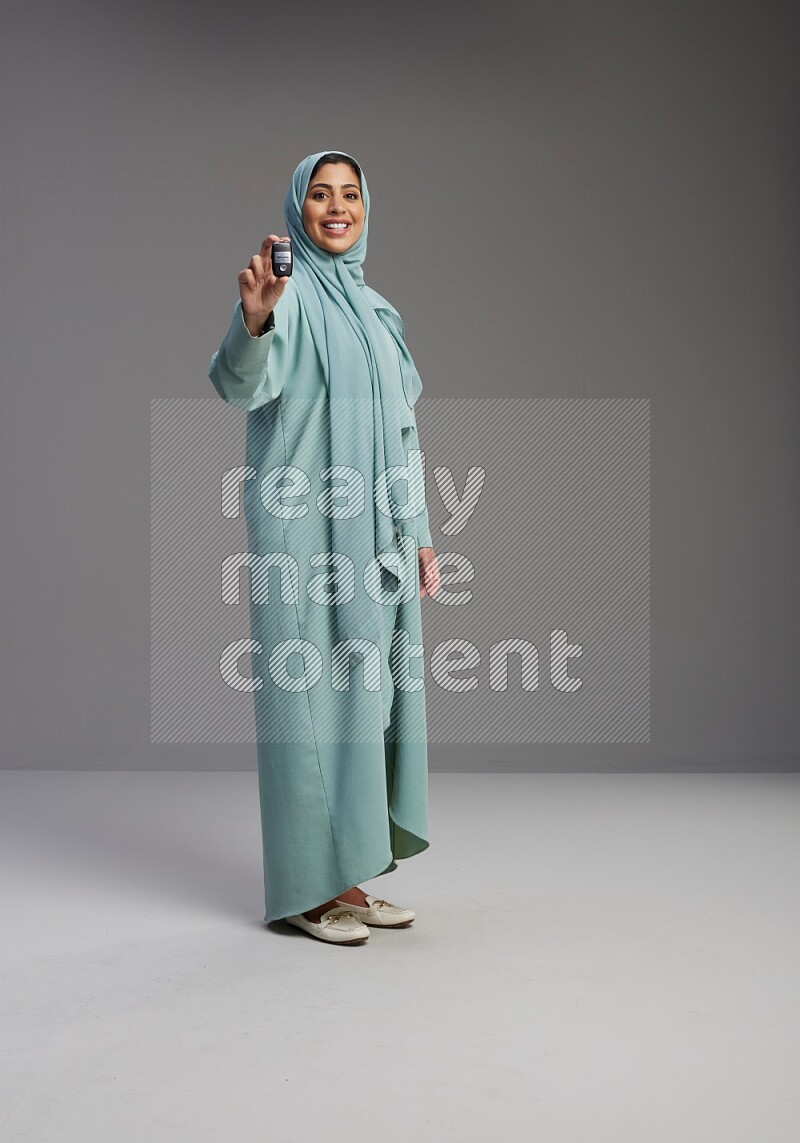 Saudi Woman wearing Abaya standing holding car key on Gray background