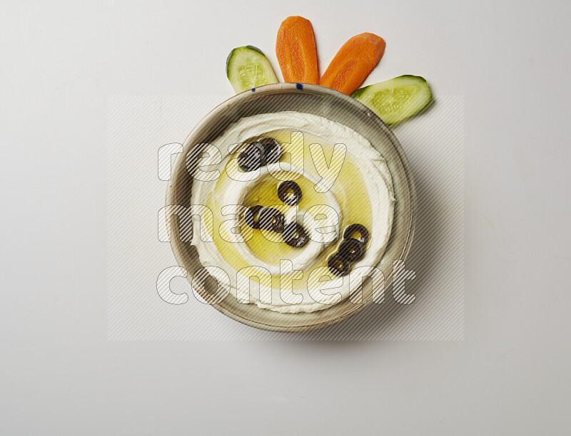 Lebnah garnished with sliced olives in a grey pottery plate on a white background