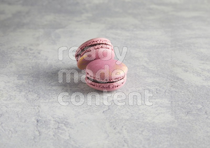 45º Shot of two Purple Strawberry macarons on white  marble background