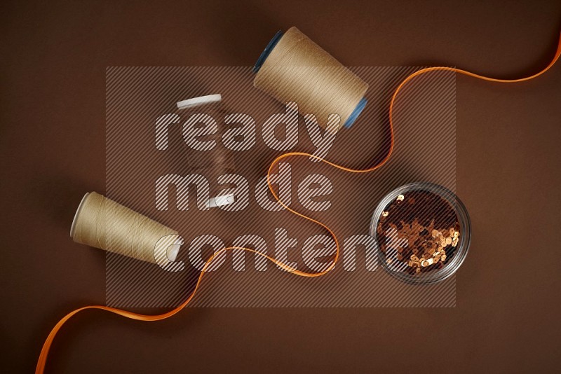 Orange sewing supplies on brown background