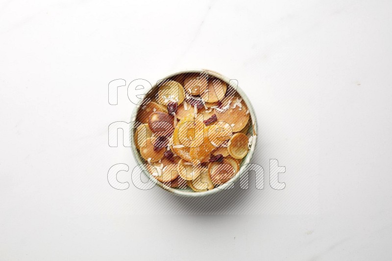 Top-view shot of orange candy cereal pancakes in a round bowl on white background