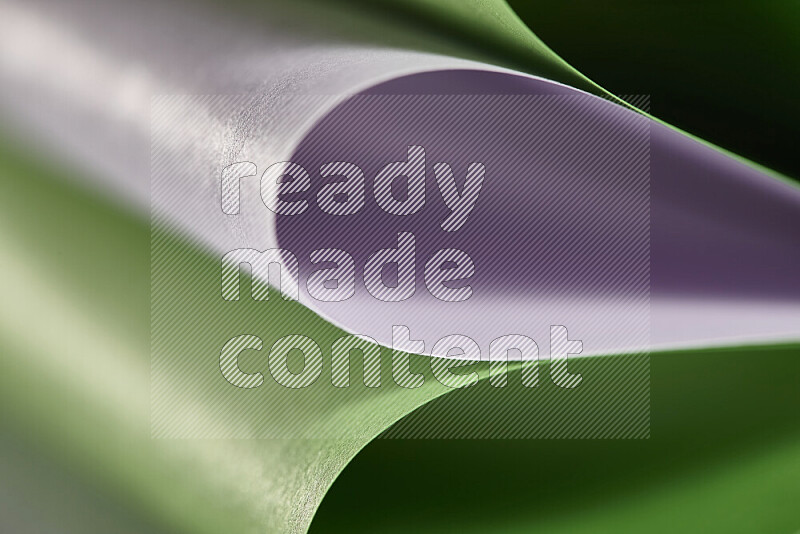 An abstract art showing purple and green paper sheets arranged in an overlapping curves