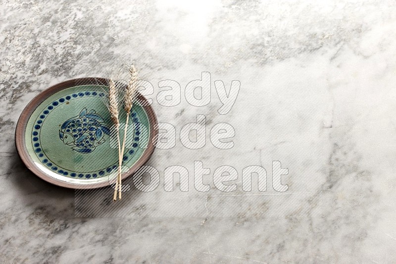 Wheat stalks on Decorative Pottery Plate on grey marble flooring, 45 degree angle